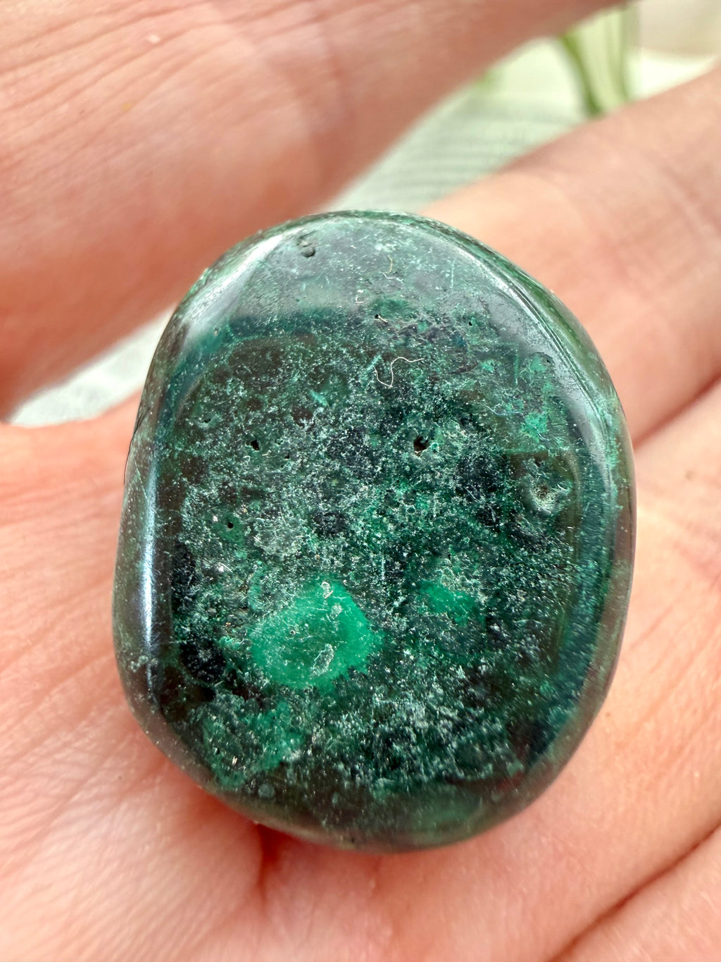 malachite  stone held in a hand with a blurred natural background