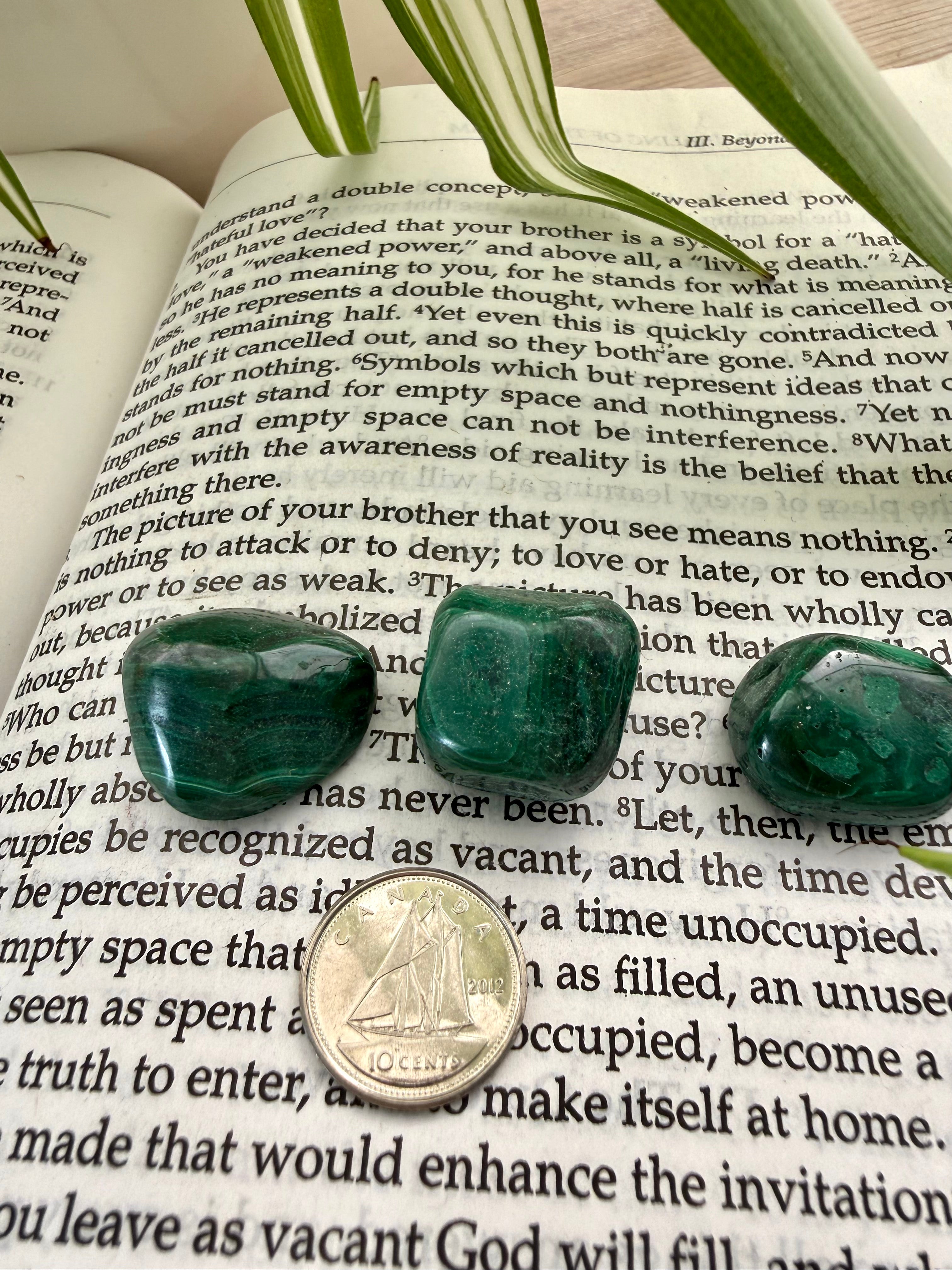 3 malachite stones on the course in miracles book with a dime to show scale 
