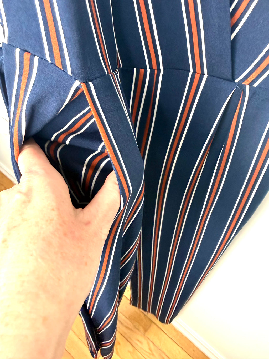 pocket detail on navy, orange and white vertical stripe jumpsuit.